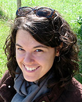 Portrait image of Molly Laas outdoors wearing a grey scarf and her sunglasses on her head