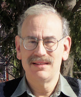 Portrait image of Richard Goodkin outdoors wearing glasses and a dark suit