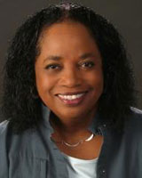 Portrait image of Thadious Davis wearing white and grey shirts and a silver necklace.