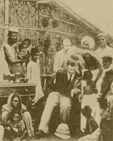 Sepia-toned image of a seated doctor in a suit attending to various Indian patients