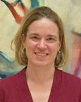 Portrait image of Anna Andrzejewski standing in front of a large modernist painting wearing a dark-pink shirt