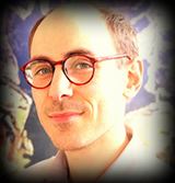 Square portrait image of Victor Goldgel-Carballo wearing a light shirt and red glasses