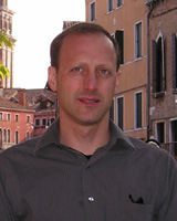 Portrait image of Todd Reeser outdoors in a European town wearing a grey-brown shirt