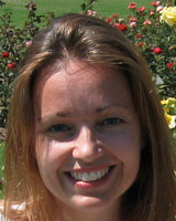 Closely-cropped portrait image of Kathryn Sanchez outdoors standing in front of rose bushes