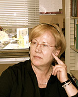 Portrait image of Ellen Sapega seated in an office wearing black with her hand at her face