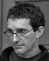 Black and White portrait image of Larry Shapiro wearing glasses and a dark shirt.