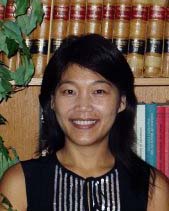 Portrait image of Cindy I-Fen Cheng in front of bookshelves wearing a black and silver dress