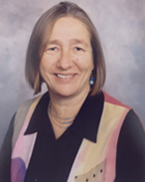 Portrait image of Susan Friedman with straight hair, long earrings, and a colorful shirt