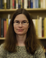 Portrait image of Andrea Westlund in front of bookshelves wearing glasses and a patterned shirt
