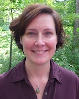 Portrait image of Kimberley Reilly outdoors wearing a purple shirt and medallion necklace