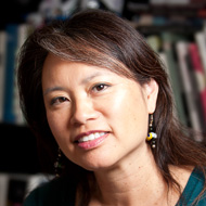 Portrait image of Leslie Bow seated in front of book shelves wearing a turquoise shirt.