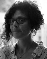 Black and White portrait image of Tina Chronopoulos wearing glasses and a polka-dot shirt