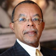 Portrait image of Henry Louis Gates, Jr. wearing glasses, black suit, and gold tie