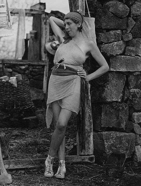 The “Baronessa,” a Viennese colonist, poses against a stone wall in a tattered costume for a film shot during the 1933 Hancock-Pacific expedition.