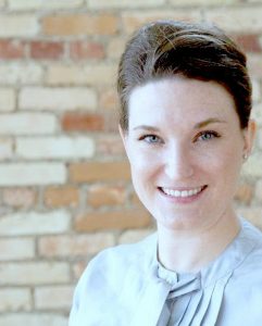 Portrait image of Katherine Robiadek wearing a light blue shirt in front of a brick wall