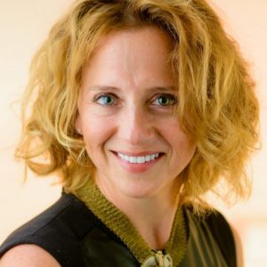 Closely-cropped portrait image of Jennifer Ratner-Rosenhagen wearing a black shirt and a gold-green necklace