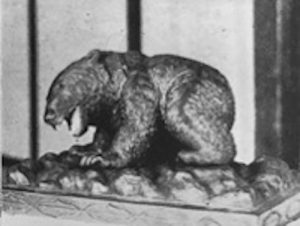 This is a black and white image of a sculpture that looks like a large animal, likely a bear on its four legs with its mouth open. 