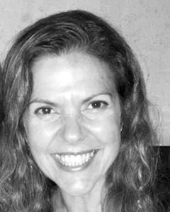 Black and white headshot photo of a smiling woman with hair down wearing a dark shirt.