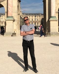 Description from subject: "Kennan Ferguson, a middle-aged white guy, standing crossarmed in front of the Louvre in Paris, somewhat pretentiously."