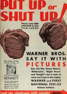 Image description: This image is an advertisement from a 1932 issue of Photoplay. On the top of the page in red lettering the image reads "Put up or shut up! There's only ONE answer to this challenge." "Warner Bros. say it with pictures." Behind the words there are two large hands making fists. 