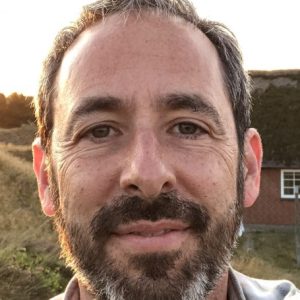 This is a close up image of Stephen Kantrowitz. he is standing outside. He is looking directly at the camera and smiling slightly.