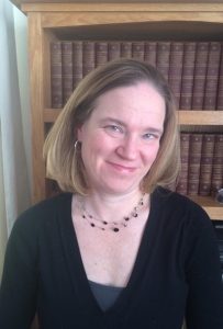 Headshot of woman with blonde hair and bookshelf behind her