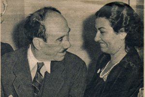 Poet Ahmad Rami and singer Umm Kulthum laughing with each other at a social event.
