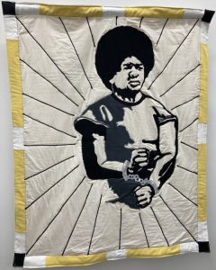 A quilt depicting a shackled Black teenager raising his fists.