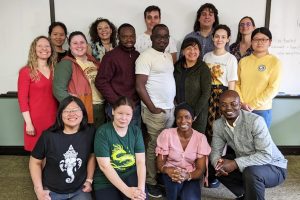 Group of smiling grad students standing before a white board