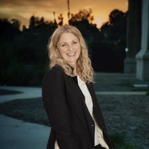 This is a photo of a woman with blonde hair standing outside at dusk