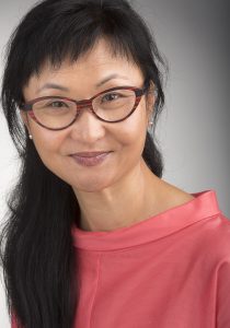 color photograph headshot of Wendy Chun with long dark hair, glasses, and a coral shirt