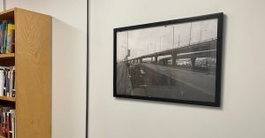 Image of poster in an office. The poster is in a black frame and depicts a black and white bridge.