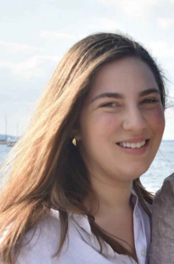 This is a headshot of a woman with short brown hair standing in front of a blurred background.